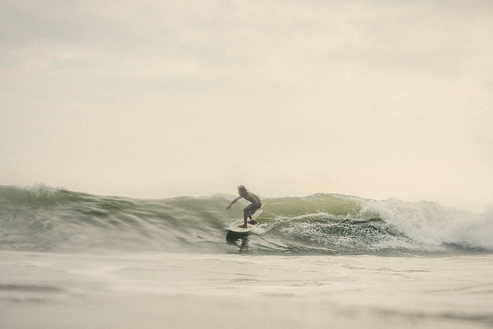 A surfer riding a soft green wave on Sri Lanka's southern coast