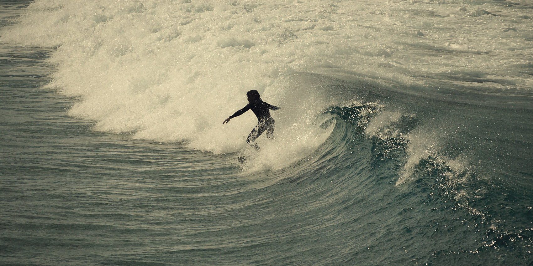 A surfer riding along the face of a breaking wave